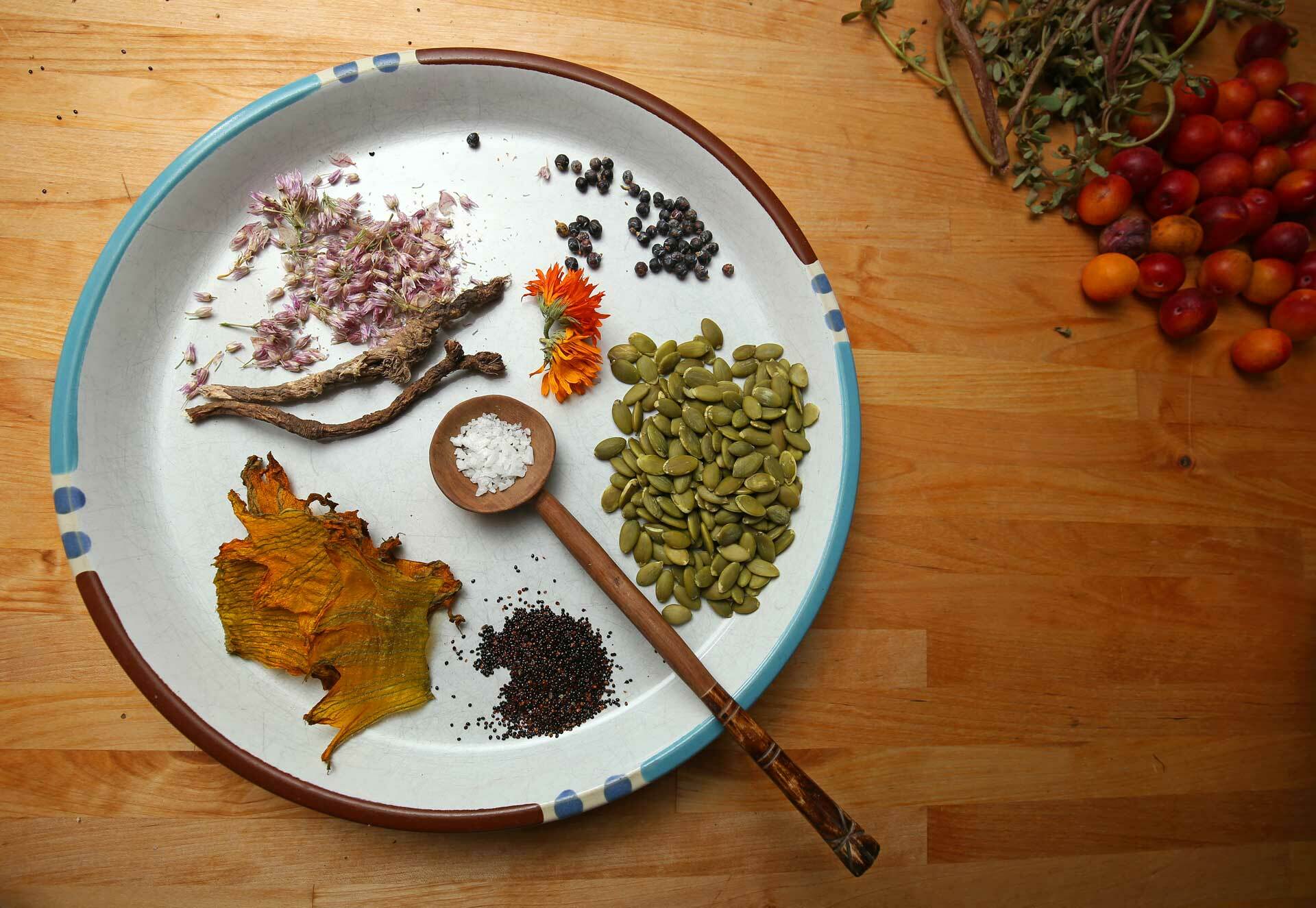 Ingredients used to season and top the coal roasted Gete Okosomin squash bisque. Clockwise: juniper berries, calendula, pumpkin seeds, salt, wild amaranth seed, dehydrated squash blossoms, biscuitroot and wild onion flowers.