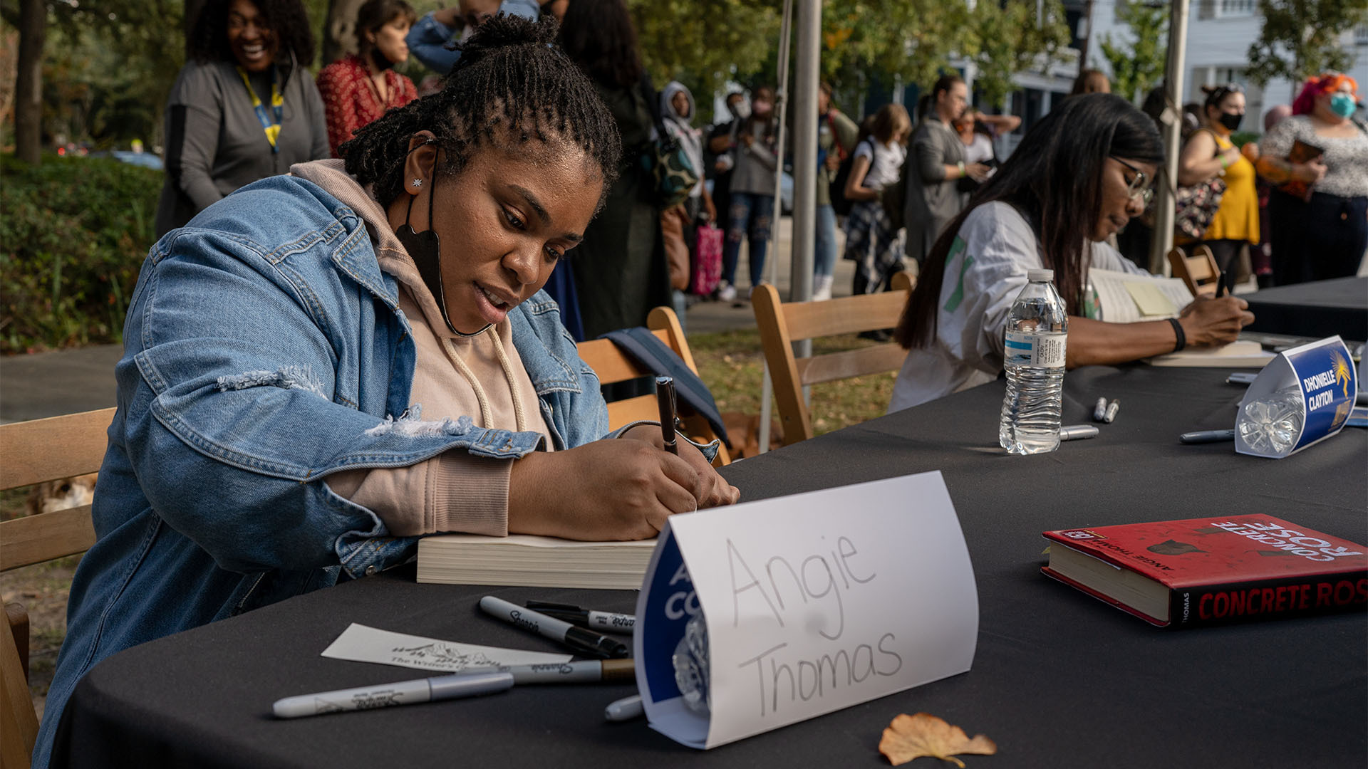 Angie Thomas signs a book at YALLFest Book Festival in Charleston, South Carolina.